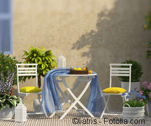 Zwei Gartenstühle an einem Gartentisch mit vielen Blumentöpfen daneben